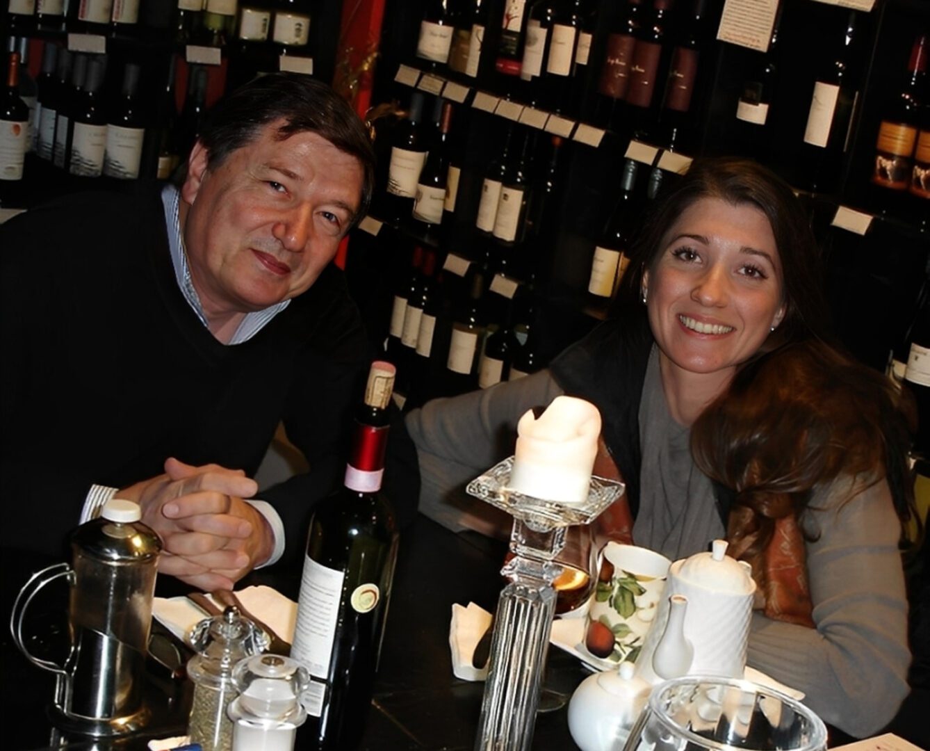 Smiling pair with wine bottles backdrop